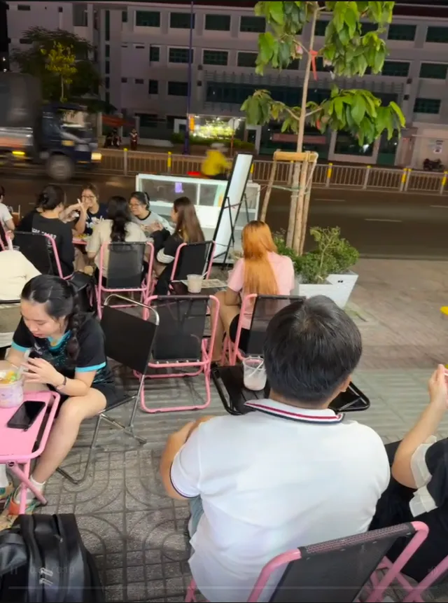 Quán đồ uống của học viên đông khách ngồi ghế nhựa hồng trên vỉa hè buổi tối