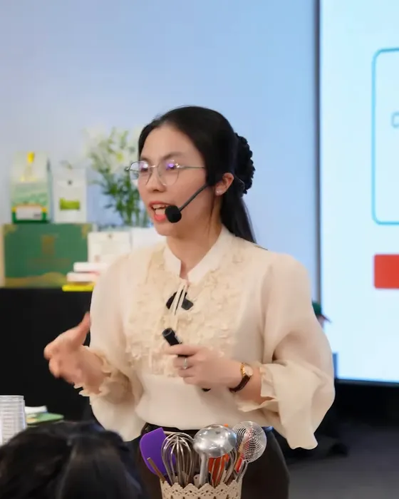 Cô Ly Phạm đeo micro giảng bài kinh doanh trước màn chiếu