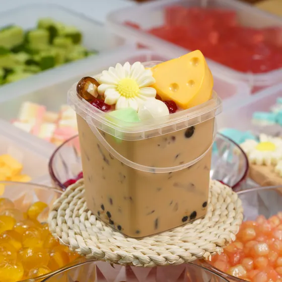 Ly trà sữa trân châu phủ kem cheese giữa các khay topping