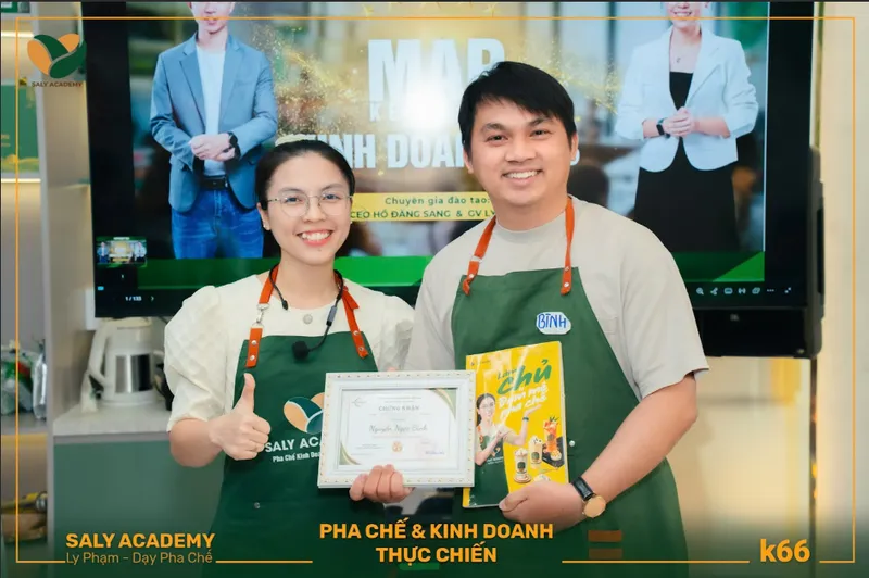 Học viên cầm giáo trình khóa pha chế và kinh doanh thực chiến chụp cùng giảng viên